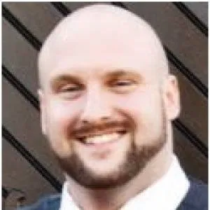Professional headshot of a smiling man in business attire